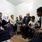 Angela Merkel, el primer ministro turco, Ahmet Davutoglu y el vicepresidente de la Comisión Europea, , Frans Timmermans, con una familia de refugiados sirios
