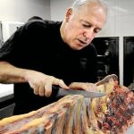 El cocinero prepara la carne a la brasa con leña de encina