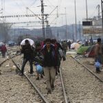 Un grupo de refugiados camina por las vías del tren en el campamento provisional de refugiados en Idomeni