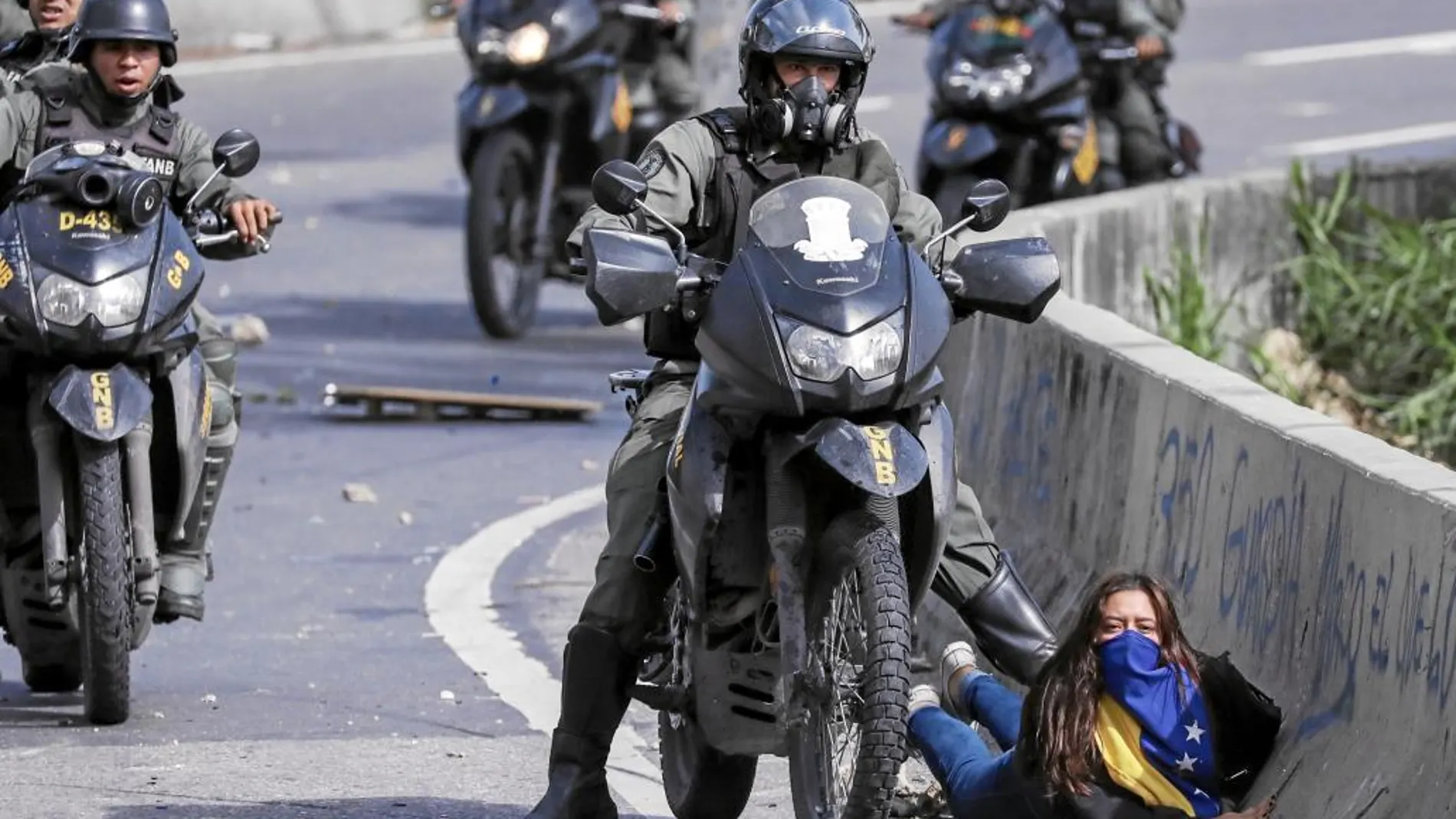 La guardia bolivariana es el brazo ejecutor de la política represiva de Maduro. Aquí un agente pisotea a una joven en Caracas