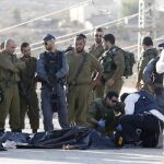 Varios policías israelíes recopilan pruebas junto al cuerpo sin vida de un palestino que ha sido abatido a tiros por un soldado israelí tras apuñalar a una joven en el asentamiento de Adam, al norte de Jerusalén y junto a la ciudad cisjordana de Ramalla, Israel el 21 de octubre de 2015.
