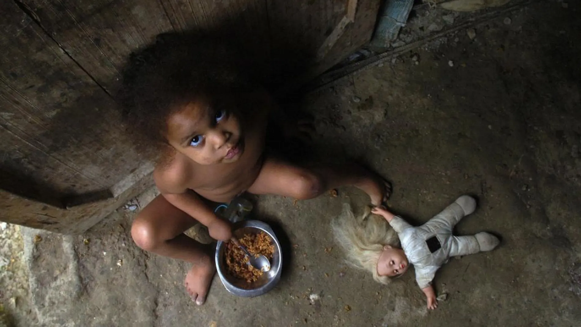 Ana Luisa de 3 años, come un plato de arroz en la puerta de su casa, en el barrio Capotillo, de la capital Dominicana donde el índice de desnutrición infantil es muy elevado