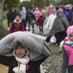 Varios refugiados abandonan el centro de registro para dirigirse hacia un autobús que les llevará a la frontera serbia.