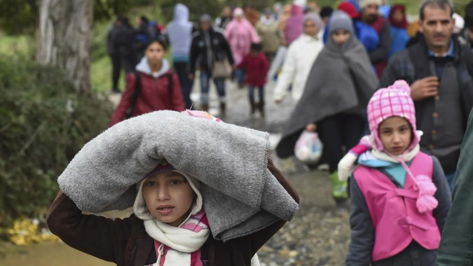 Varios refugiados abandonan el centro de registro para dirigirse hacia un autobús que les llevará a la frontera serbia.