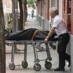 Operarios de la funeraria trasladan el cadáver de una mujer, de 55 años que ha sido hallado hoy en una vivienda en Sevilla con un arma blanca en el pecho.