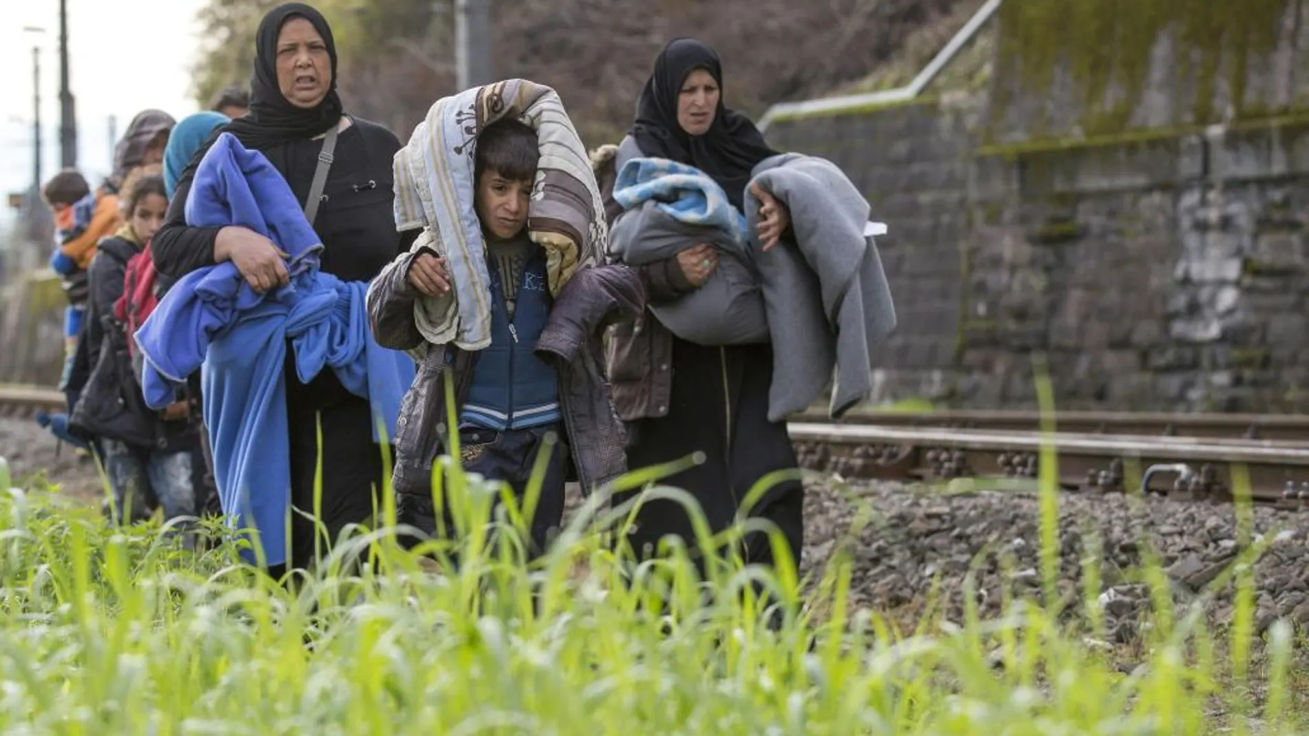 Refugiados caminan por las vías del tren en la frontera entre Austria y Eslovenia en Spielfeld (Austria).