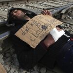 Un refugiado protesta en contra del cierre de las fronteras en las vías del tren del campamento provisional de Idomeni.