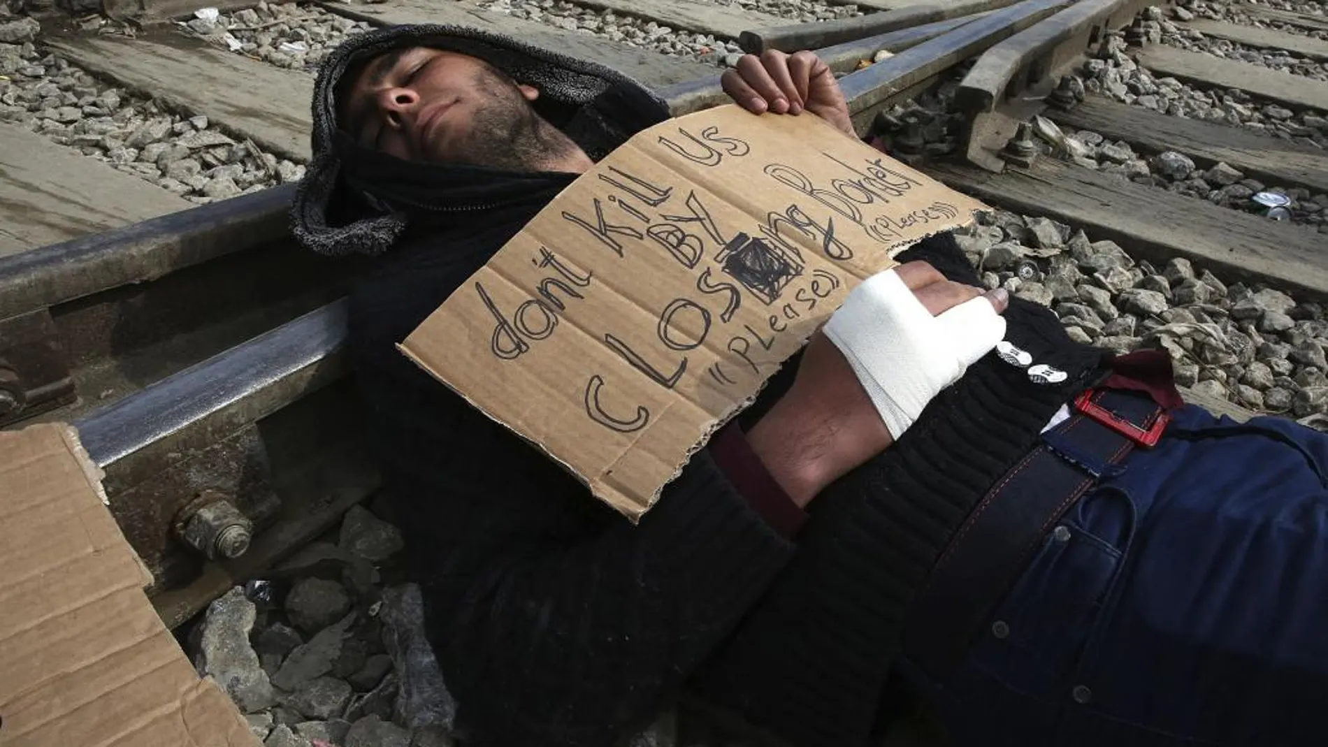 Un refugiado protesta en contra del cierre de las fronteras en las vías del tren del campamento provisional de Idomeni.