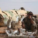 Un miembro de las Fuerzas de Siria Democrática junto a un avión destruido en el aeropuerto de Tabqa cerca de raqa