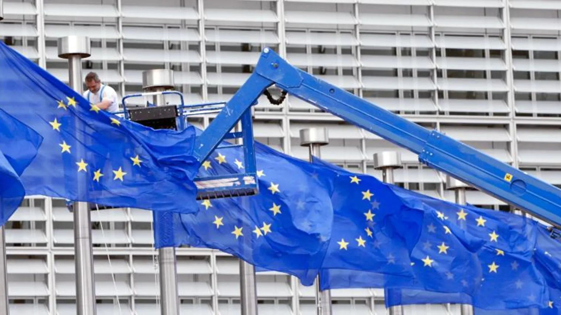 Un trabajador arregla una de las banderas de la sede de la Unión Europea en Bruselas el 23 de julio, día del referéndum británico