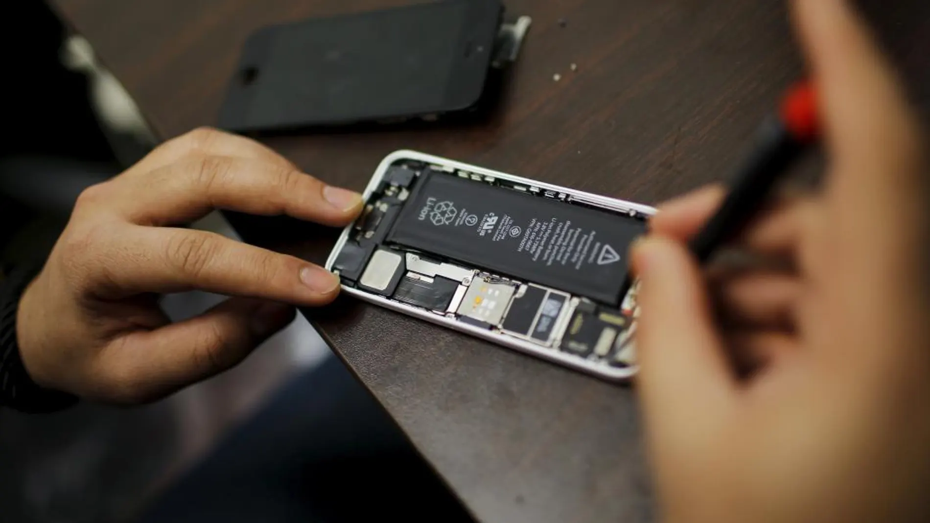 Un trabajador trata de reparar un iPhone en una tienda de Nueva York