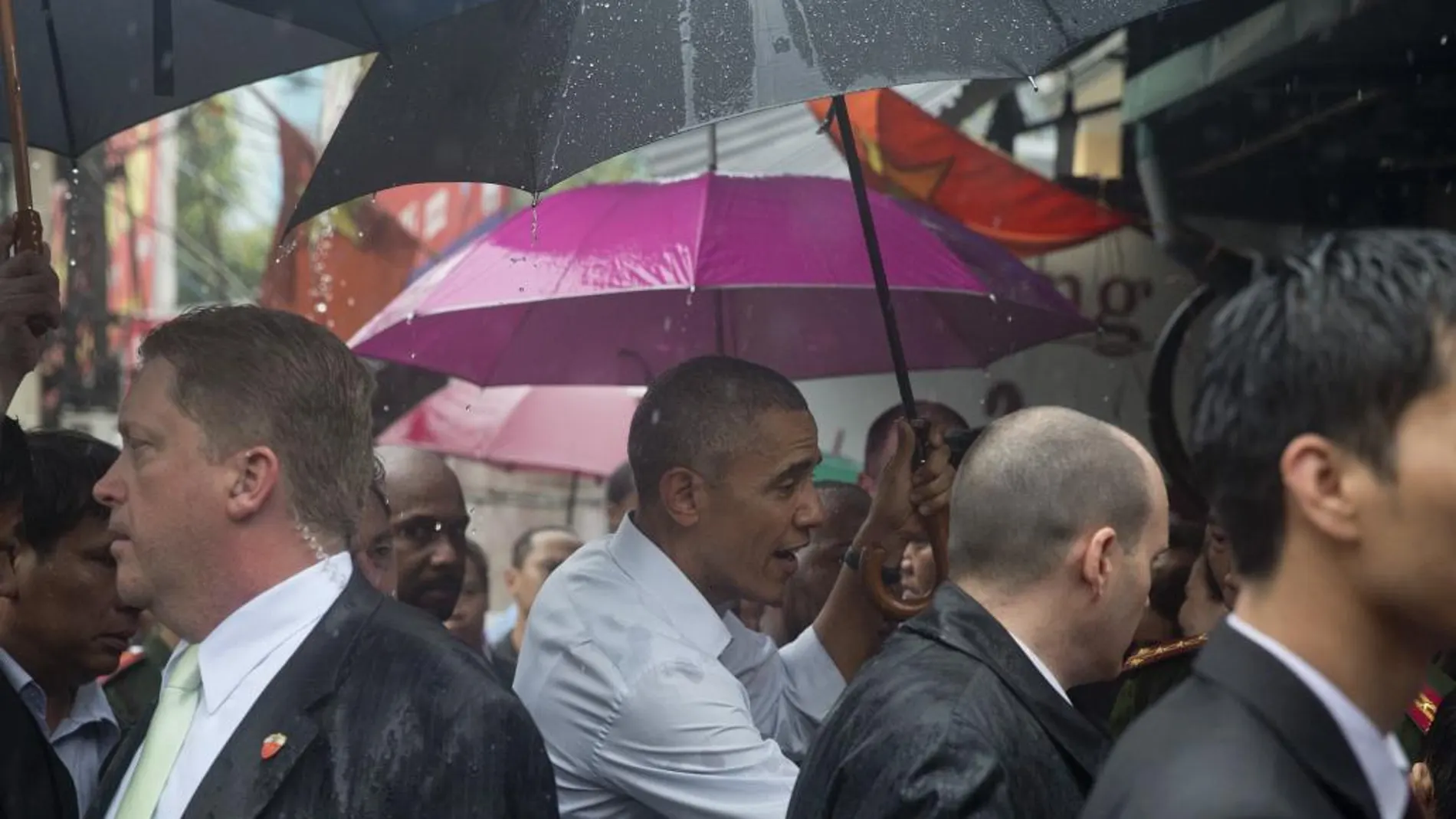 Obama se protege de la lluvia con un paraguas durante su visita a una zona comercial de Hanoi