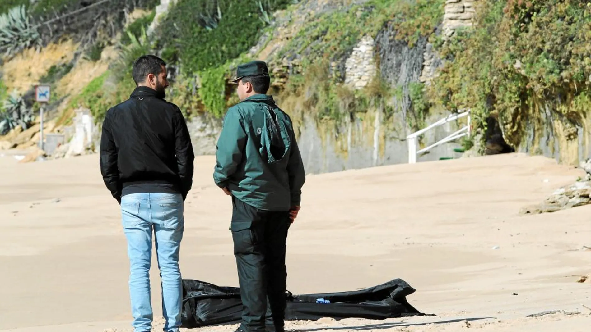 Agentes de la Guardia Civil ante el cadáver de un inmigrante en la playa de Caños de Meca, en la localidad gaditana de Barbate. Doce siguen sin aparecer