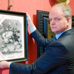 El director de los Uffizi muestra la reproducción en blanco y negro del lienzo de Huysum que se expone en el museo florentino con la mención de «robado» en italiano, inglés y alemán
