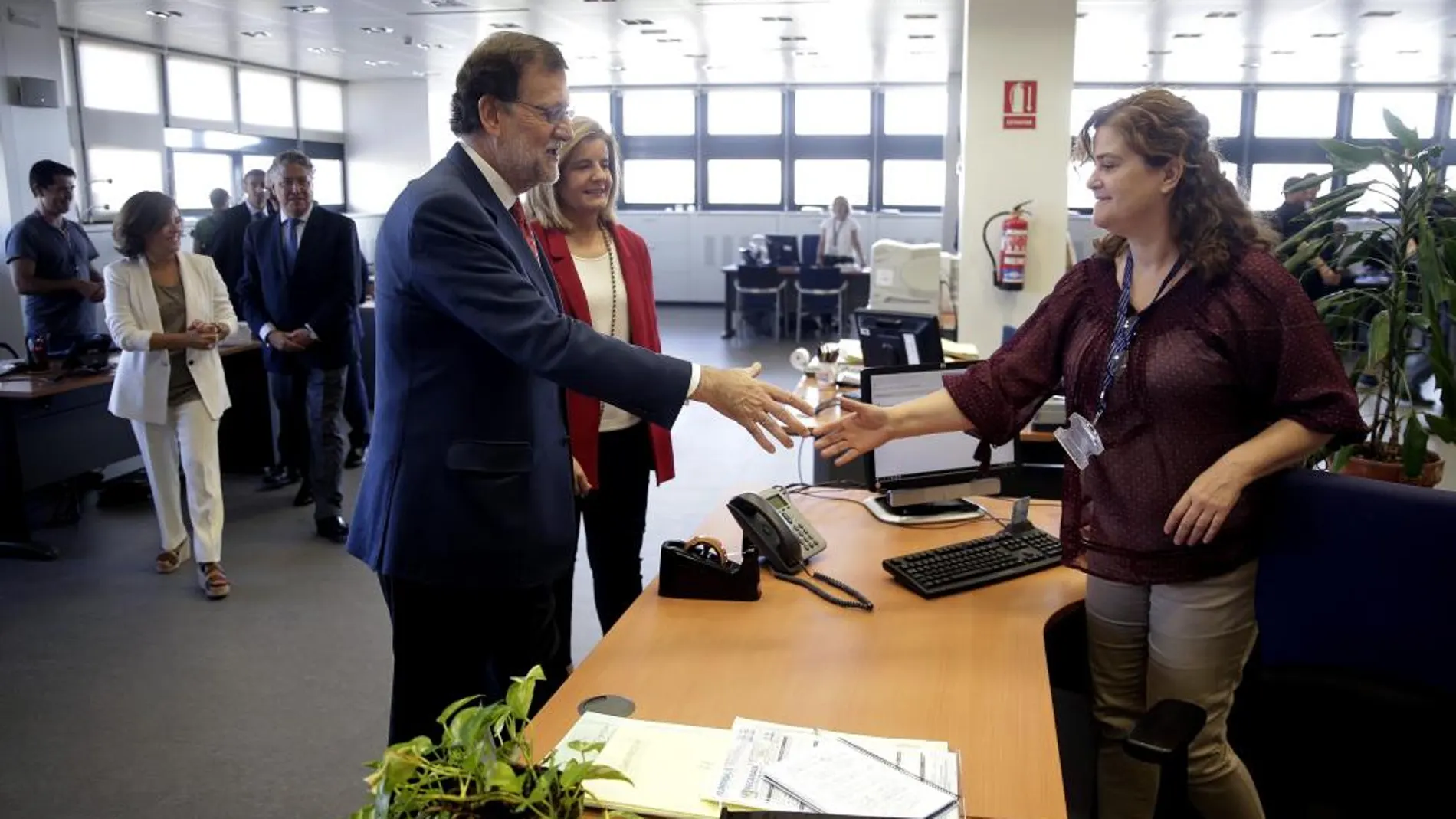 El presidente del Gobierno en funciones, Mariano Rajoy, acompañado por la ministra de Empleo, Fátima Báñez, entre otros, saluda a una trabajadora de la Seguridad Social.