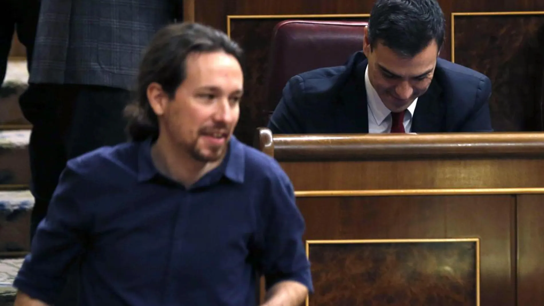 El líder de Podemos, Pablo Iglesias, pasa delante del escaño del secretario general del PSOE, Pedro Sánchez