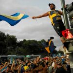 Un aficionado de Boca Juniors despide al equipo en Buenos Aires subido en un semáforo