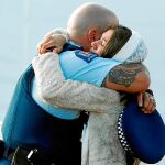 Un familiar de una víctima abraza a un policía durante los entierros múltiples por las víctimas en Christchurch, ayer / Reuters