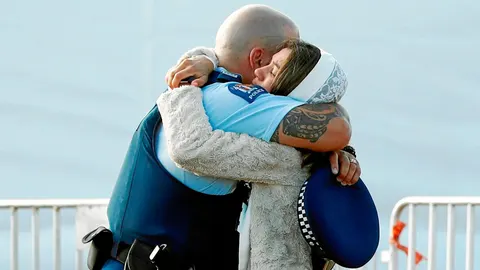 Un familiar de una víctima abraza a un policía durante los entierros múltiples por las víctimas en Christchurch, ayer / Reuters