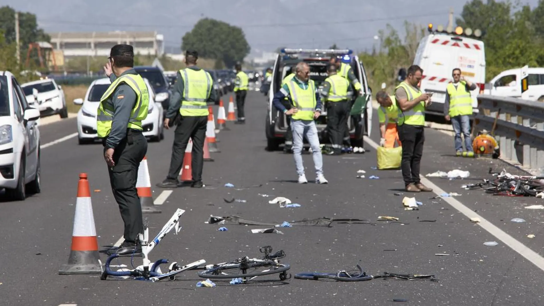 Agentes de la Guardia Civil y miembros de Emergencias en Oliva, donde una conductora de un turismo, que dio positivo en alcohol y drogas arrolló a un grupo de seis ciclistas.