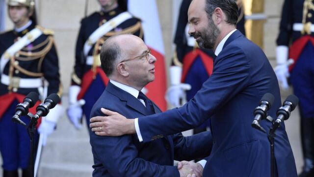El primer ministro francés, Èdouard Philippe (dcha.) saluda afectuosamente a su antecesor, Bernard Cazeneuve