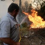 Un vecino apaga las llamas en Louriceira, Portugal/Reuters