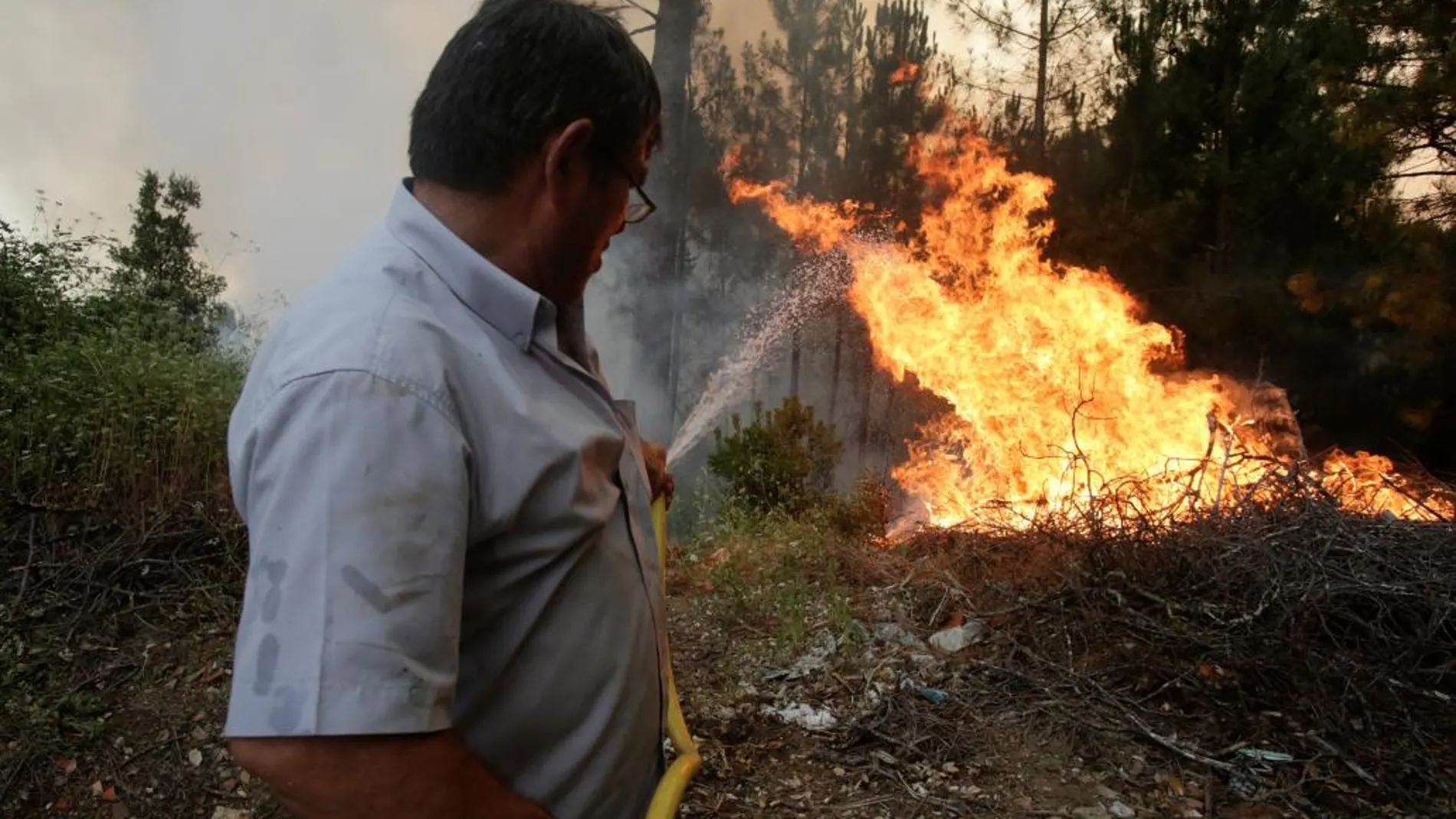 Un vecino apaga las llamas en Louriceira, Portugal/Reuters