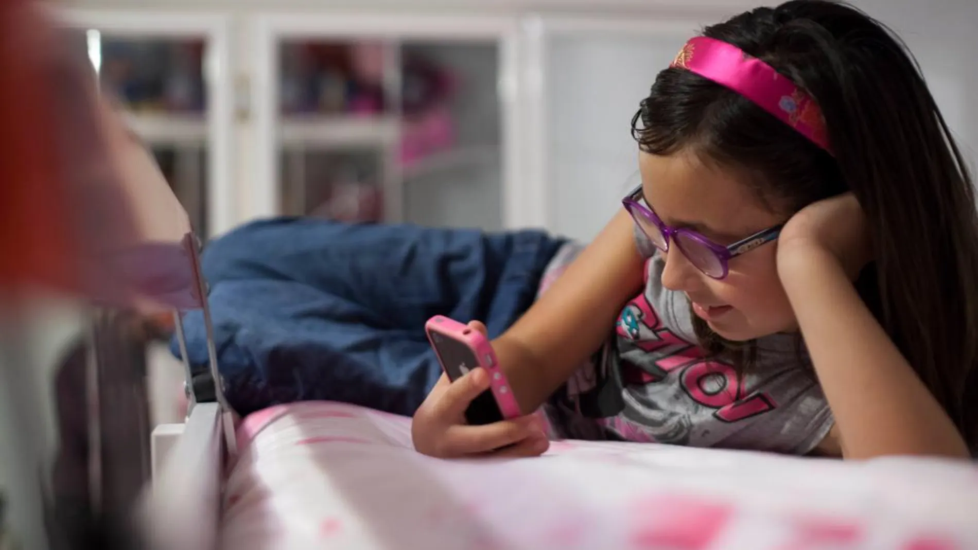Una niña juega con su móvil en casa / Gonzalo Pérez
