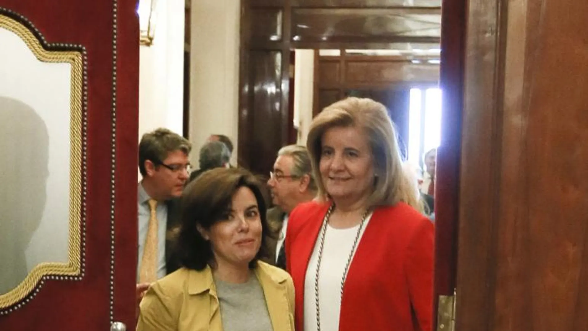 La vicepresidenta del Gobierno, Soraya Saénz de Santamaría,iz. y la ministra de Empleo, Fátima Báñez, en los pasillos del Congreso de los Diputados.