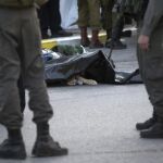 Agentes de seguridad israelíes permanecen junto al cuerpo del palestino que atacó a una pareja de israelíes en una estación de servicio