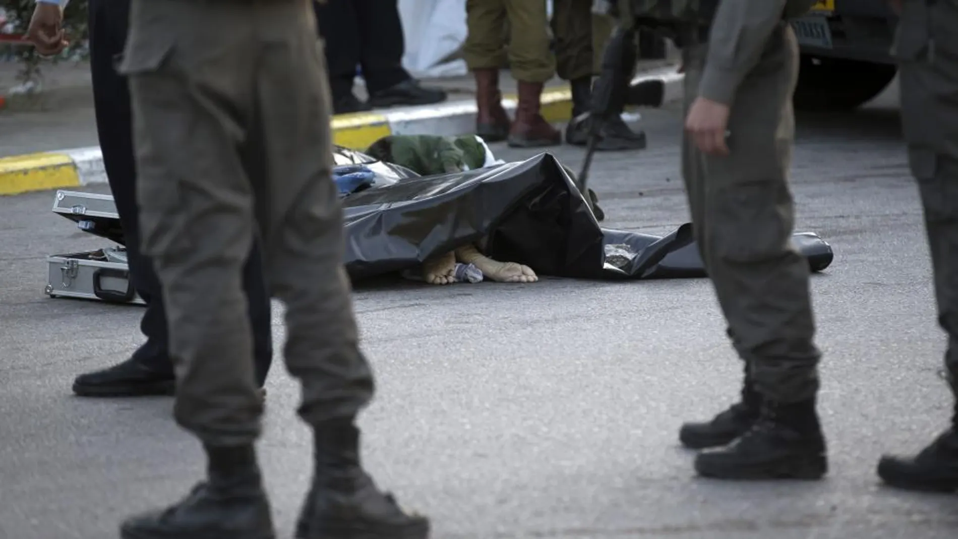 Agentes de seguridad israelíes permanecen junto al cuerpo del palestino que atacó a una pareja de israelíes en una estación de servicio