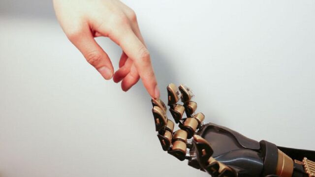 Un dedo humano toca un dedo robótico, revestido con piel artificial