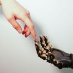 Un dedo humano toca un dedo robótico, revestido con piel artificial