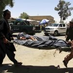 Un hombre afgano es trasladado en camilla tras resultar herido en el atentado suicida frente a una sucursal bancaria