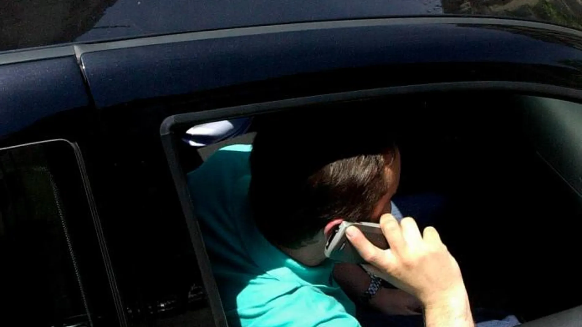 Dos jóvenes hablan por teléfono dentro de un coche
