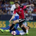 El defensa del Alavés, Carlos Vigaray, se lleva el balón ante el centrocampista del Málaga, Javi Ontiveros