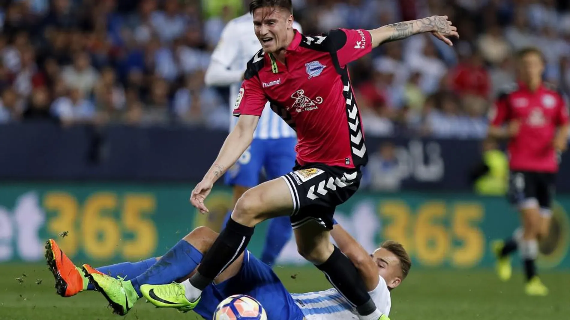 El defensa del Alavés, Carlos Vigaray, se lleva el balón ante el centrocampista del Málaga, Javi Ontiveros