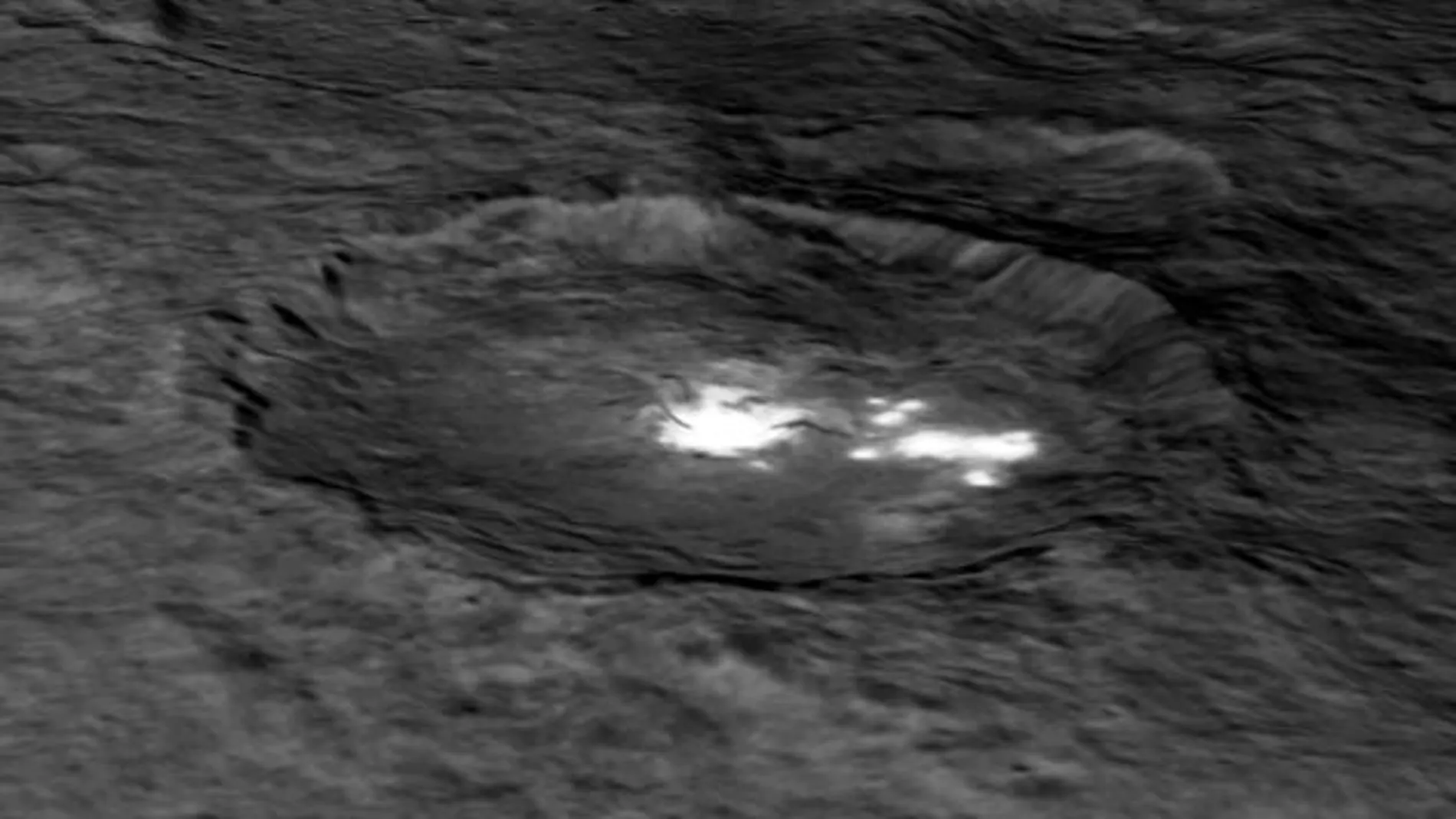 Cráter Occator de Ceres, donde se observan varios puntos brillantes y otro cráter interior de unos diez kilómetros de diámetro y medio kilómetro de profundidad