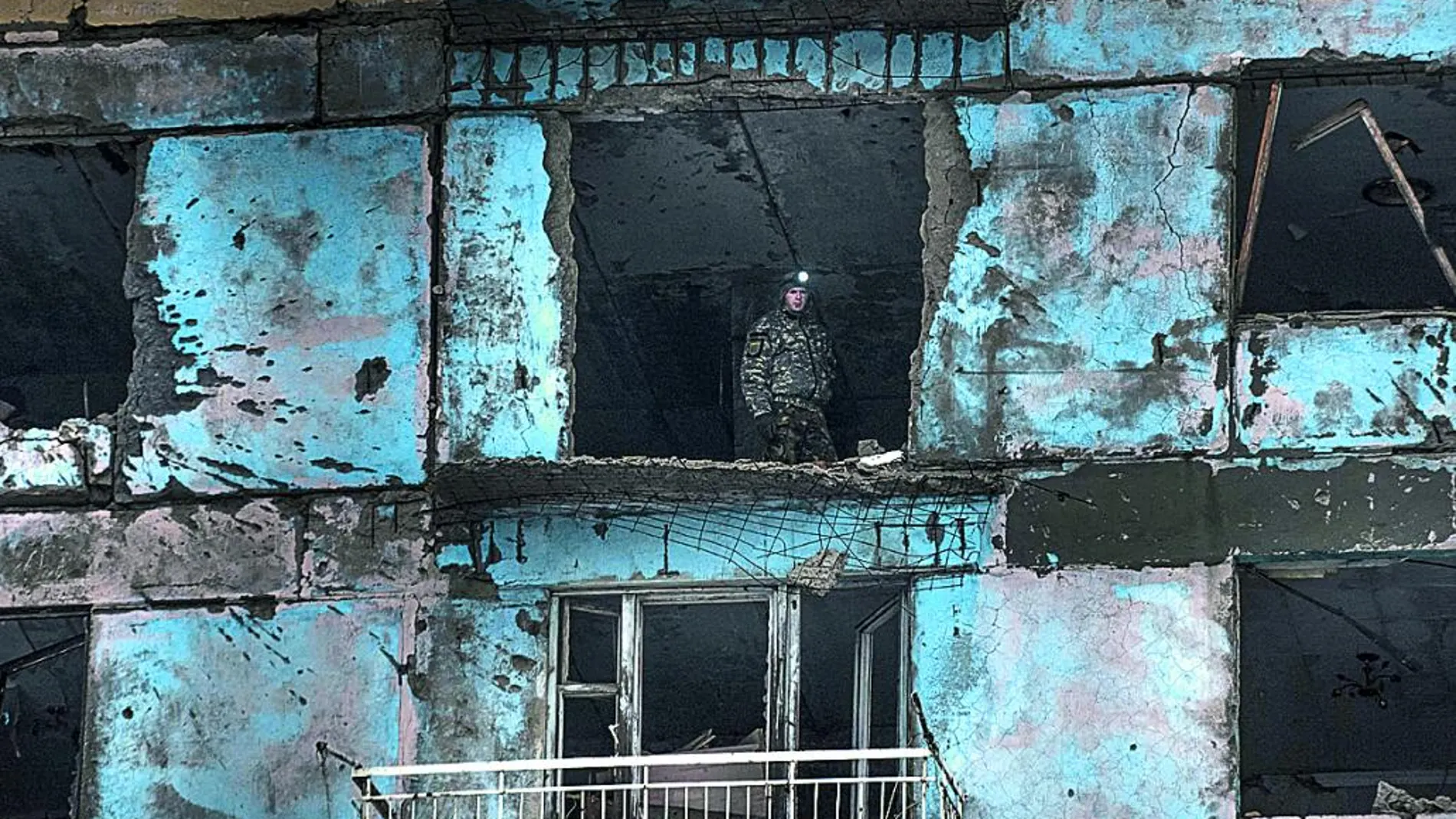 Un soldado ucraniano patrulla desde un edificio golpeado durante los combates