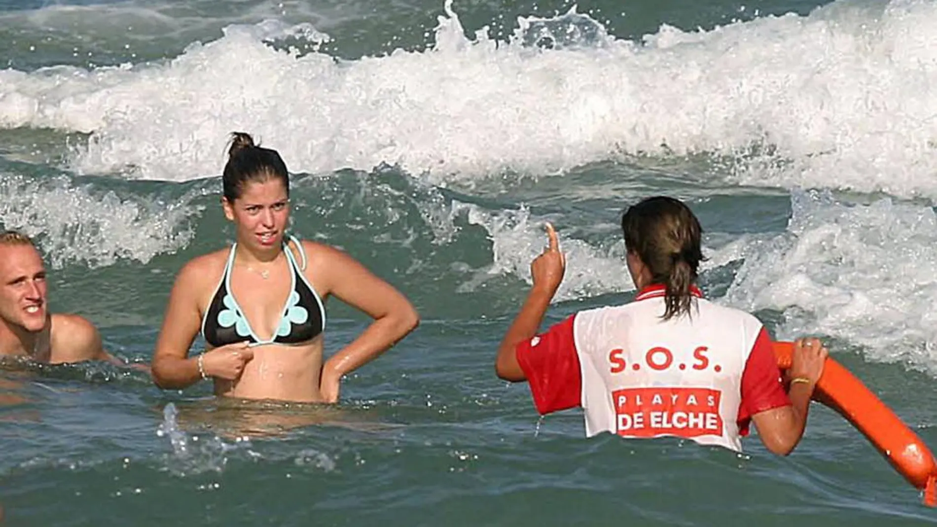 Una socorrista advierte a varias bañistas sobre el peligro de bañarse cuando el mar no está calmado