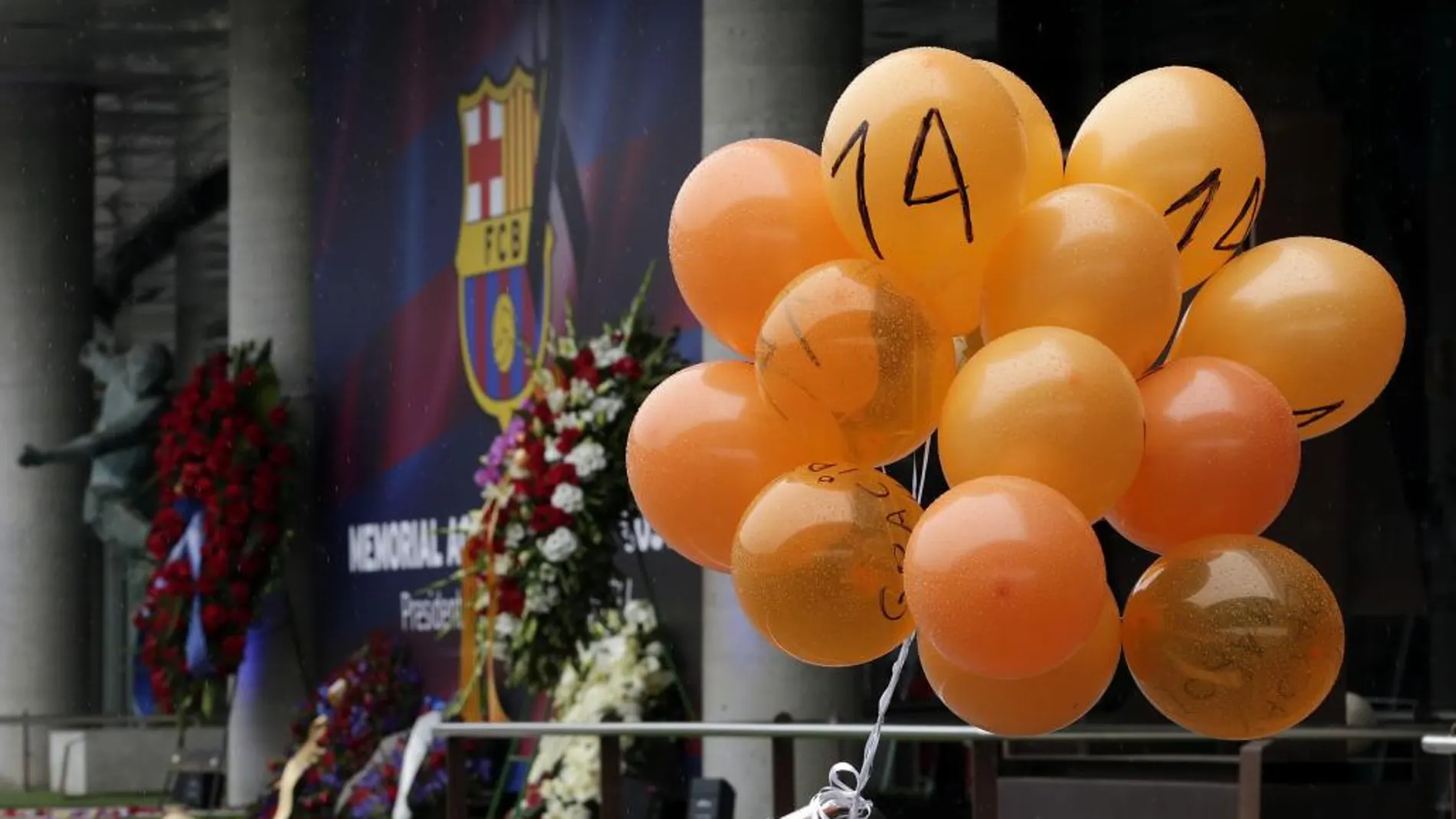 Unos cuantos globos de color naranja con el número 14 que han sido dejados por un aficionado ante la puerta de tribuna del Camp Nou, en recuerdo del primer aniversario de la muerte de Cruyff