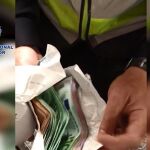 Un agente sostiene dos sobres de dinero incautados a los detenidos