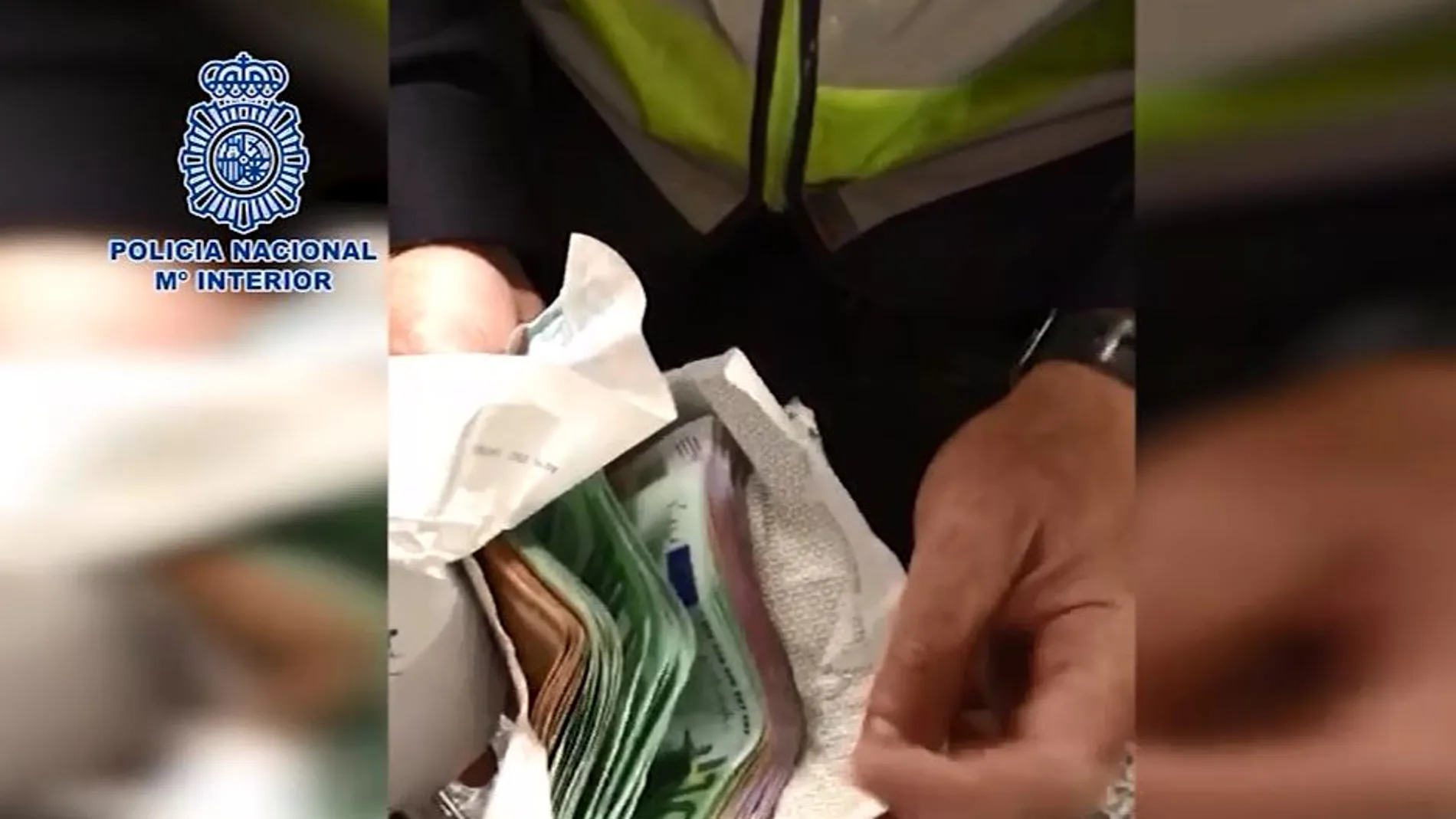 Un agente sostiene dos sobres de dinero incautados a los detenidos