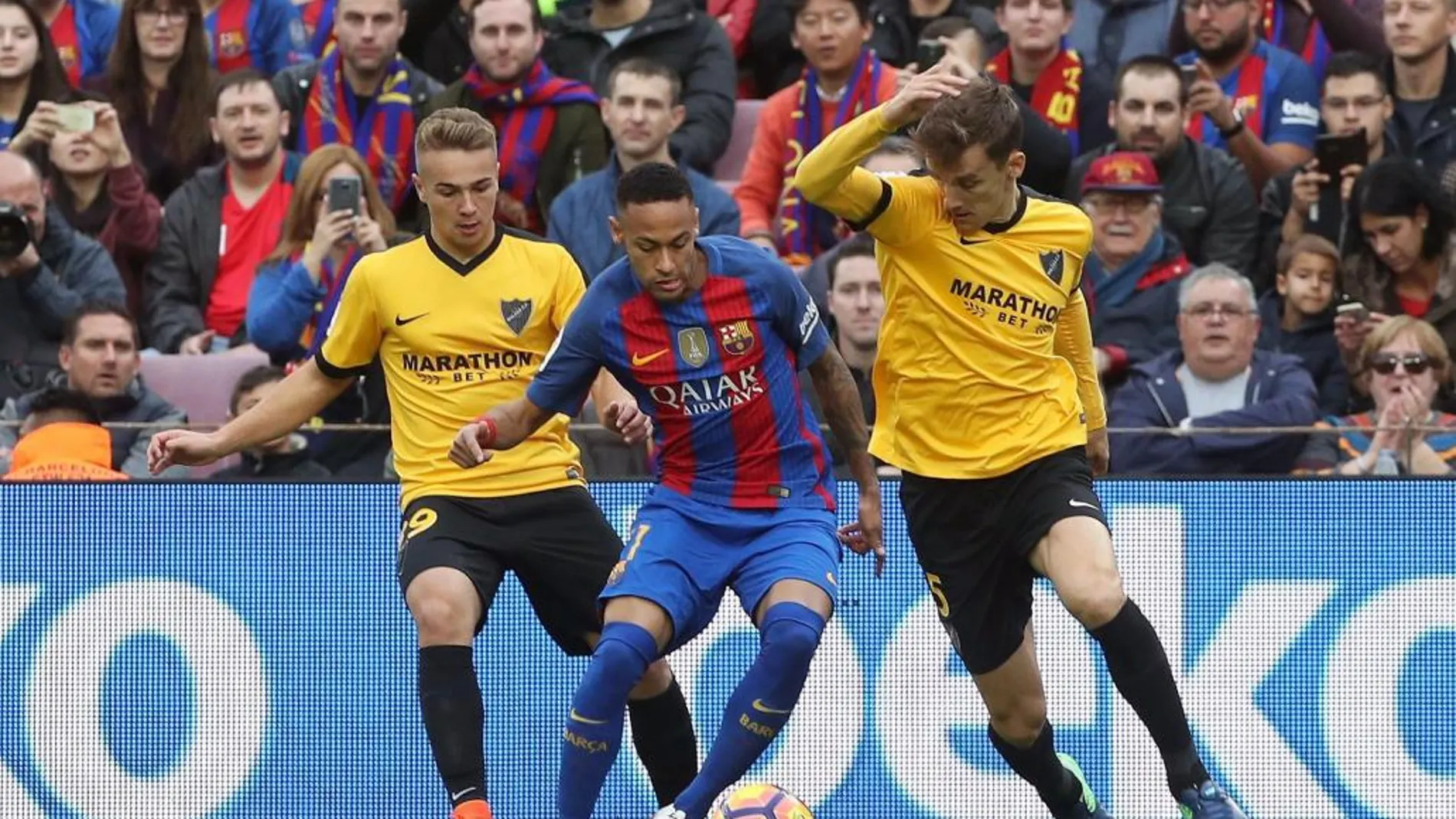 El delantero brasileño del FC Barcelona Neymar jr intenta avanzar con el balón ante el centrocampista Javier Ontiveros y el defensa Diego Llorente, del Málaga CF