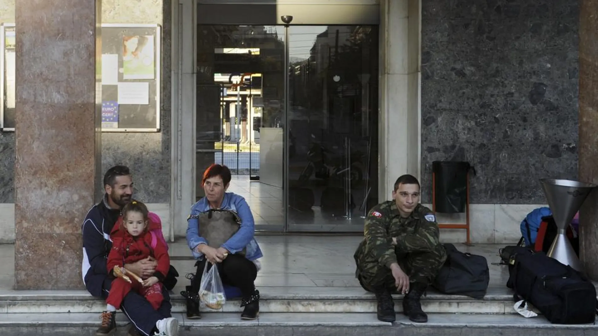 Un grupo de personas espera ante la puerta de la estación de tren de Atenas