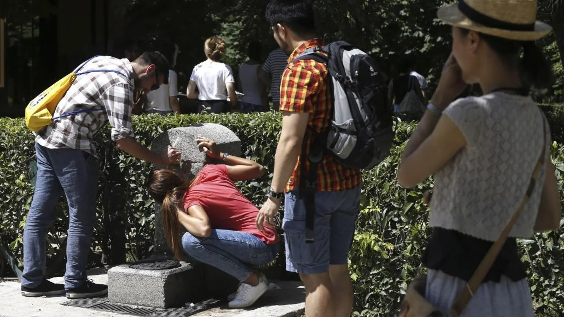 Varias personas se refrescan hoy en una fuente del parque del Retiro de Madrid