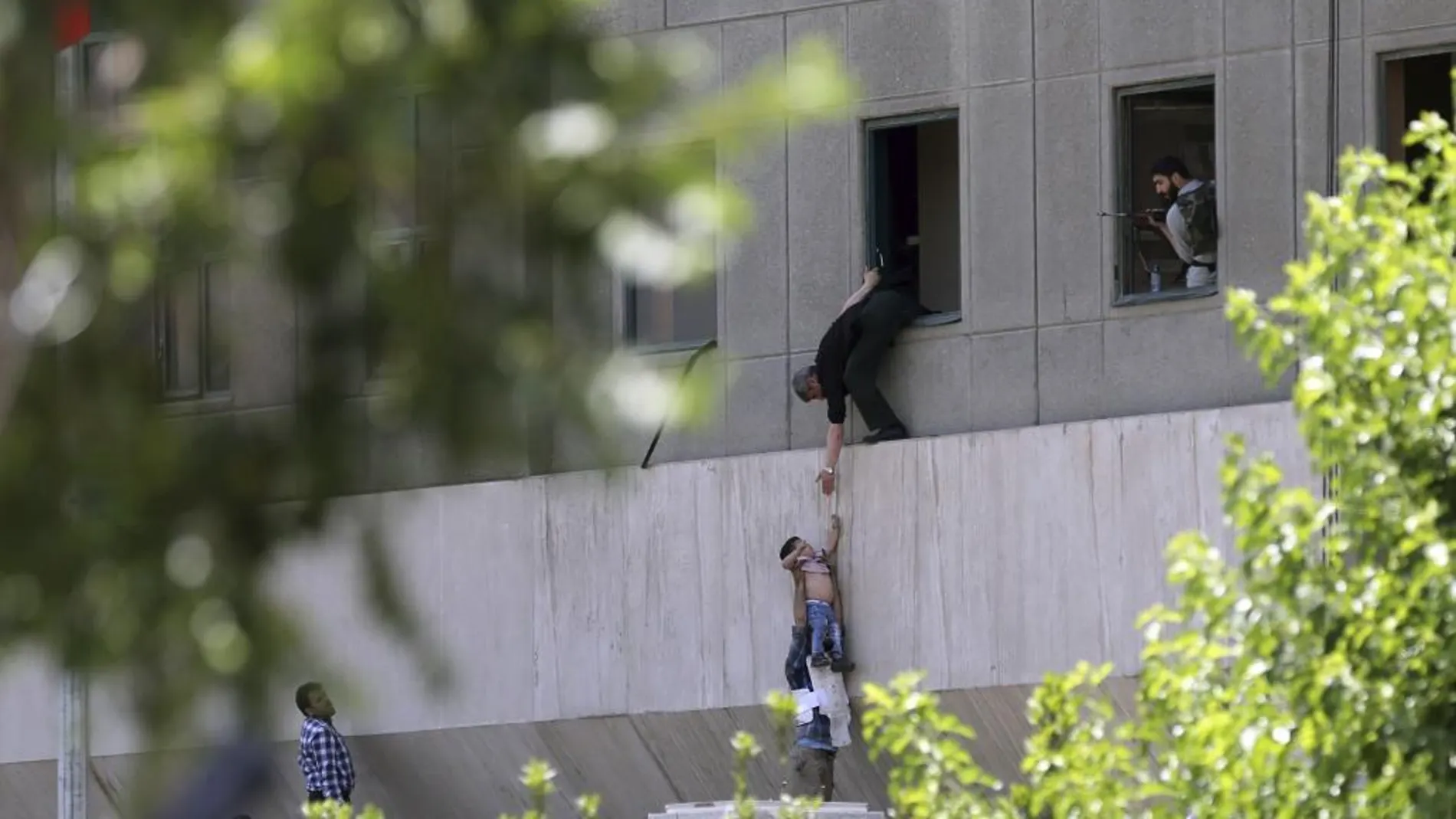 Un policía pone a salvo a un niño tras la irrupción de los terroristas en el Parlamento iraní