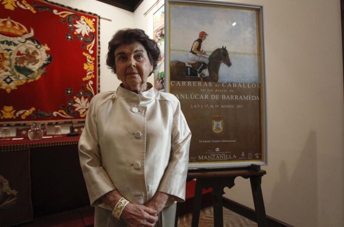 La pintora sevillana Carmen Laffón, junto al cartel de las Carreras de Sanlúcar