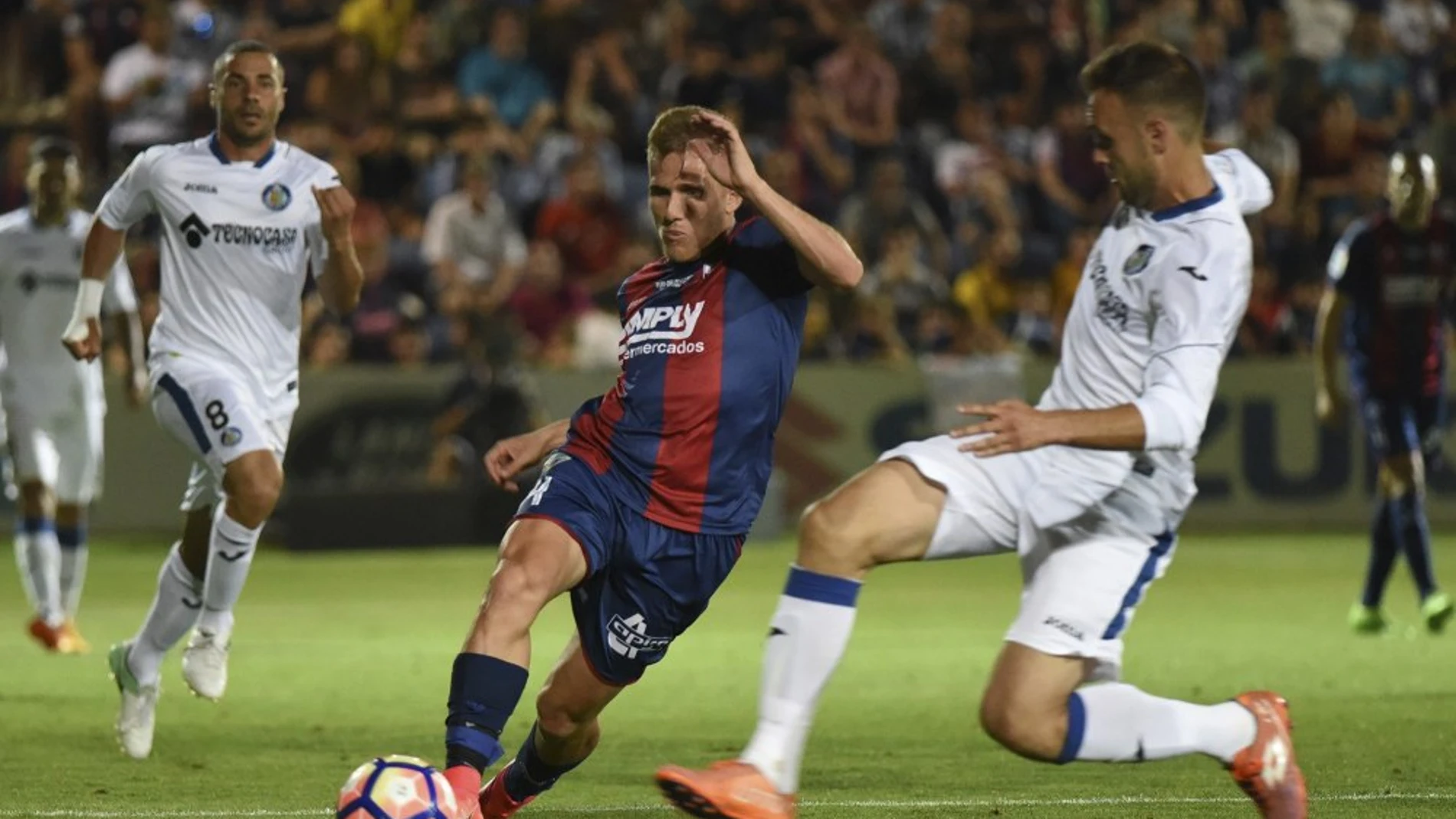 El centrocampista del Huesca, Samuel Sáiz, controla el balón junto un jugador del Getafe.