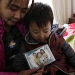 Mei Qiuyu (izda) y su hijo Wang Zhongsheng (dcha) muestran una fotografía de su otra hija y su marido en su casa en el distrito de Daxing en Pekín